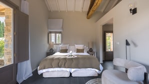 Une chambre avec un grand lit, des tables de chevet, une chaise et une fenêtre.