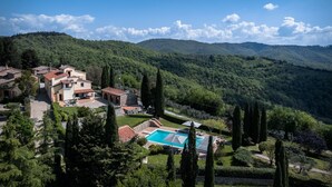 Une villa avec piscine, entourée d’une végétation luxuriante et de collines.