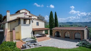 Une maison à deux étages dotée d’un patio, d’un espace salon extérieur et d’une arche en pierre.
