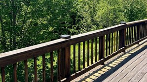 Een houten terras met een balustrade met uitzicht op een dicht bos.