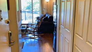Un pasillo que conduce a una sala de estar con un sofá, un sillón mecedor y una mesa de comedor.