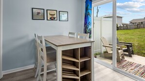 A dining area with a table and chairs, a sliding glass door leading to a backyard, and three framed pictures on the wall. - Oceanside Condo in Atlantic Beach, NC-Anchors Away Unit 3 (Atlantic Beach)