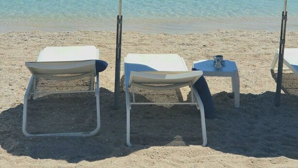 A beach with two blue umbrellas, white lounge chairs, and a small table with a cup. - Quiet villa top with shared pool. Close to port and beaches. (Toulon)
