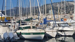 A marina with multiple sailboats docked, surrounded by buildings and hills in the background. - Quiet villa top with shared pool. Close to port and beaches. (Toulon)