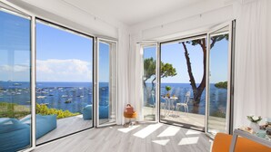 Une chambre moderne dotée de grandes portes-fenêtres coulissantes, d’un plancher en bois et offrant une vue sur la mer et les bateaux.