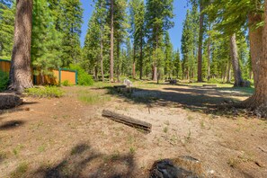 Un terrain de camping avec un sentier de terre, des bancs en bois et un petit bâtiment.