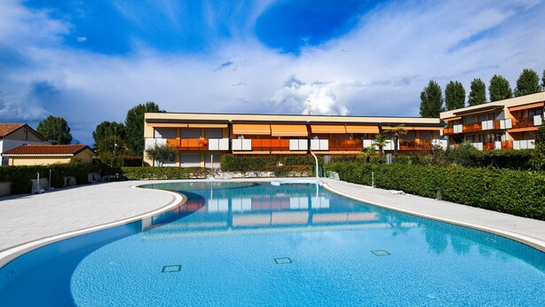 Um hotel moderno com piscina, apresentando um design de piscina curvilíneo e um telhado plano.