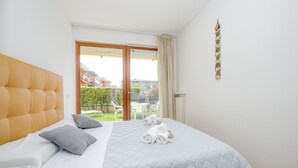 Quarto de hotel com uma cama grande, vista para um jardim e uma porta de correr de vidro.