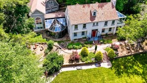 A large, two-story house with a red door, surrounded by lush greenery and a well-maintained garden. - 8 Bedroom MANSION Biltmore Lake with Hot Tub. (Biltmore Lake)