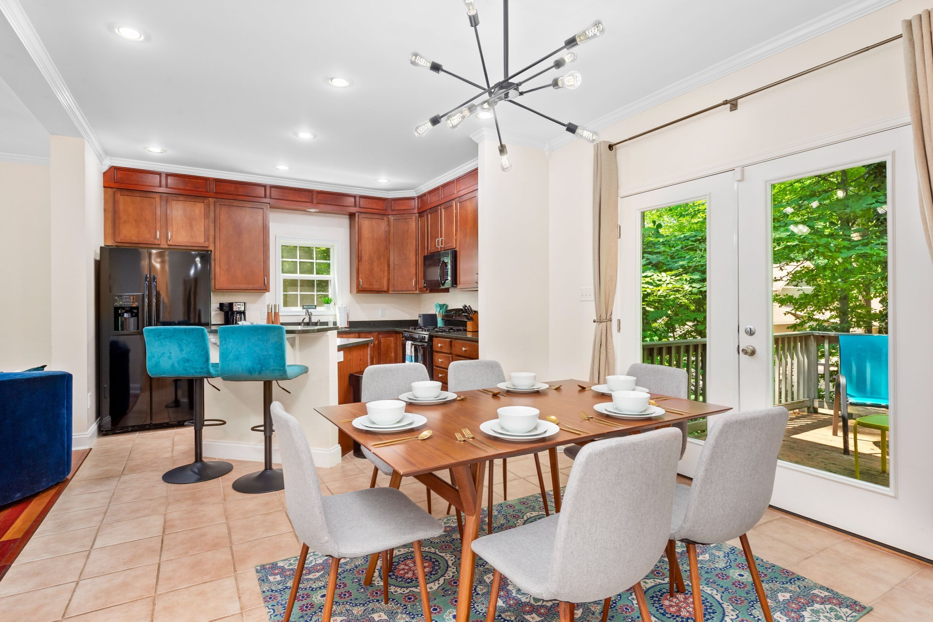 A modern kitchen with wooden cabinets, a stainless steel refrigerator, and a dining area with a wooden table and chairs.