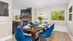 A dining area with a brick fireplace, a large dining table set for six, and blue chairs. - 8 Bedroom MANSION Biltmore Lake with Hot Tub. (Biltmore Lake)