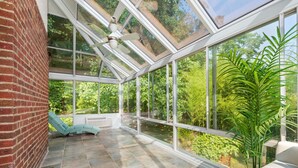 A conservatory with a glass ceiling, a brick wall, and a view of greenery outside. - 8 Bedroom MANSION Biltmore Lake with Hot Tub. (Biltmore Lake)
