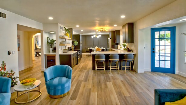 Una cocina moderna con una isla central, taburetes de bar y una zona de comedor.