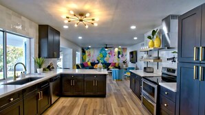 Una cocina moderna con armarios oscuros, una isla central y un llamativo mural abstracto en la pared.