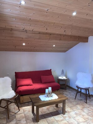 Une pièce chaleureuse avec un canapé rouge, une table basse en bois et un fauteuil blanc moelleux.
