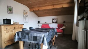 A dining area with a table set for four, a wooden cabinet, and a red sofa. - 1st floor, view mountain, parking, tv, ski locker, 42m², Le Grand Bornand (Le Grand-Bornand)