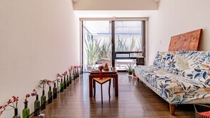 Una sala de estar moderna con un sofá, una mesa de centro y una hilera de jarrones con flores.