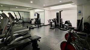 Un gimnasio con cintas de correr, máquinas de pesas y un muro de espejos.