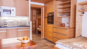 A compact kitchen with a microwave, coffee maker, and a bed with a wooden headboard. - 3rd floor, balcony, parking, tv, 24m², Le Grand Bornand (Le Grand-Bornand)