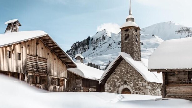A rustic wooden building with a stone church tower and a cross, surrounded by snow-covered mountains. - 3rd floor, balcony, parking, tv, 24m², Le Grand Bornand (Le Grand-Bornand)