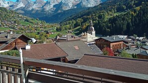 A mountainous village with traditional wooden houses and a church, surrounded by forested hills and mountains. - 3rd floor, balcony, parking, tv, 24m², Le Grand Bornand (Le Grand-Bornand)