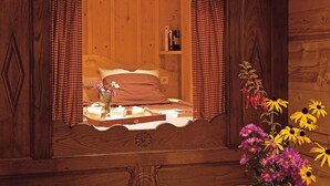 A wooden room with a bed, a shelf with books, and a vase with flowers. - 100m from ski slopes, Ground floor, fitness, swimming pool, sauna, tv, ski locker, 60m² (Le Grand-Bornand)