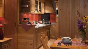 A cozy kitchen with wooden cabinets, a dining table set for four, and a vase of flowers on the right. - 100m from ski slopes, Ground floor, fitness, swimming pool, sauna, tv, ski locker, 60m² (Le Grand-Bornand)
