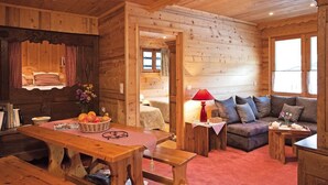 A wooden cabin interior with a dining table, bench, sofa, and a cozy living area. - 100m from ski slopes, Ground floor, fitness, swimming pool, sauna, tv, ski locker, 60m² (Le Grand-Bornand)
