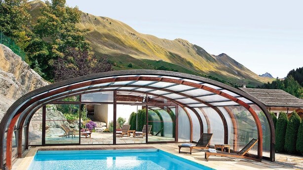 A swimming pool with a glass-enclosed patio area, surrounded by mountains. - 100m from ski slopes, Ground floor, fitness, swimming pool, sauna, tv, ski locker, 60m² (Le Grand-Bornand)