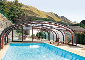 Une piscine dotée d’un patio entièrement vitré, le tout entouré de montagnes.