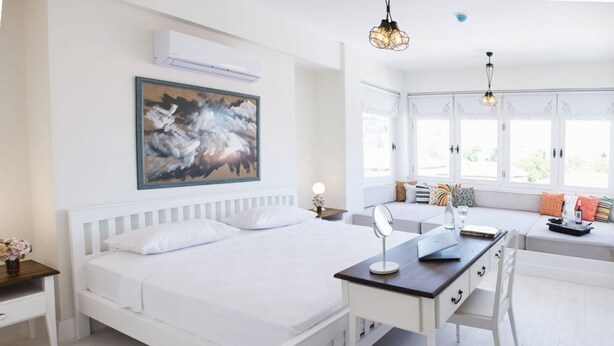 A bedroom with a white bed, a desk, and a large window with a view. - Puka Otel Alacatı (Cesme)