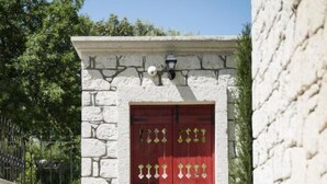 A stone building with a red door and a small garden area with stepping stones leading to the door. - Puka Otel Alacatı (Cesme)