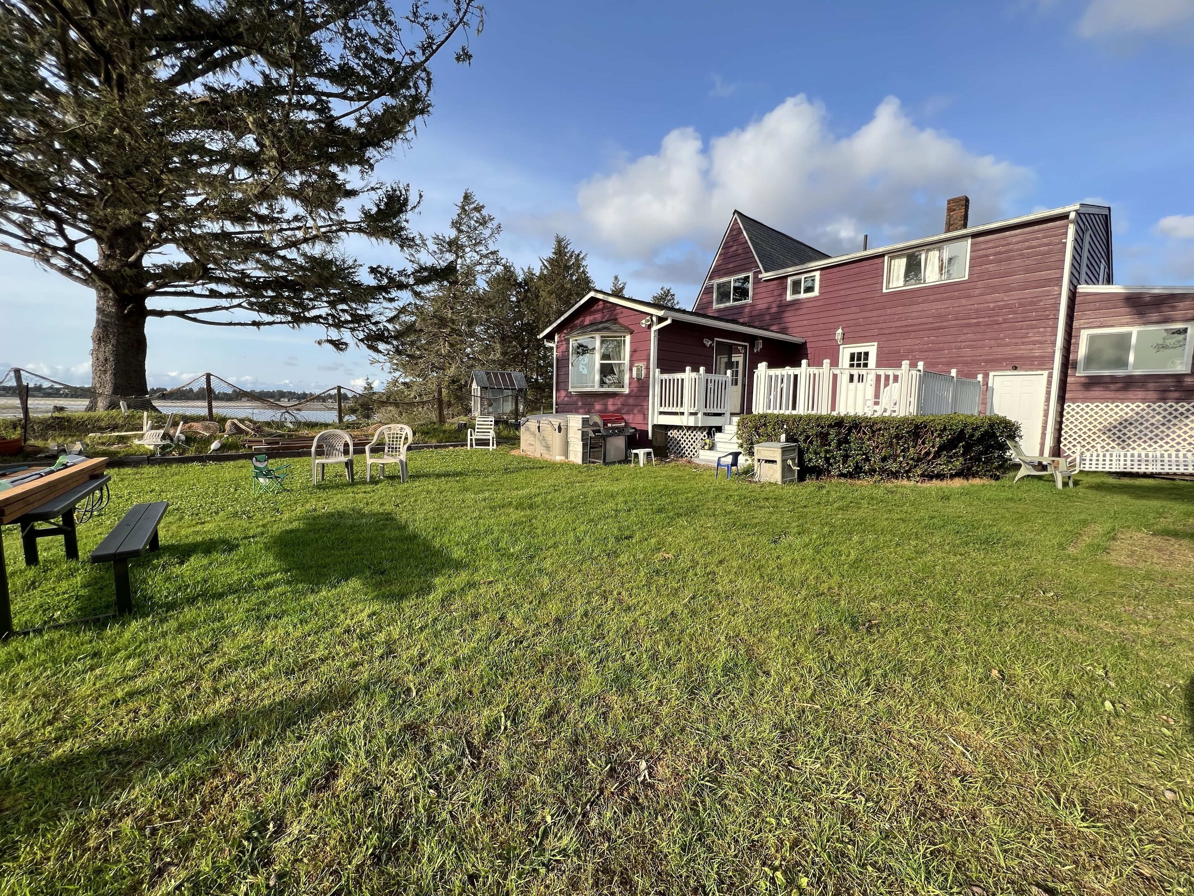 A house with a large yard, a picnic table, and a fenced area with chairs.