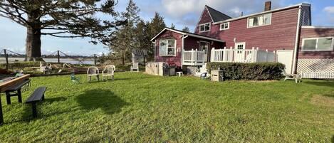 A house with a large yard, a picnic table, and a fenced area with chairs.