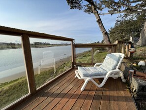 A wooden deck with a white lounge chair and a view of a river. - Larger River Front home with Views of the Estuary and peak views of the Ocean (Seaside)