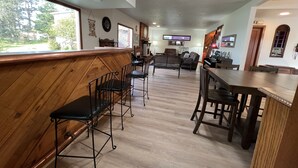 Een ruime woonkamer met een houten bar, zitplaatsen, een open haard en een televisie.