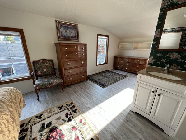 A room with a wooden dresser, a chair, a rug, a painting, and a window. - Larger River Front home with Views of the Estuary and peak views of the Ocean (Seaside)