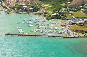 An aerial view of a marina with numerous boats docked, a breakwater, and surrounding residential areas.