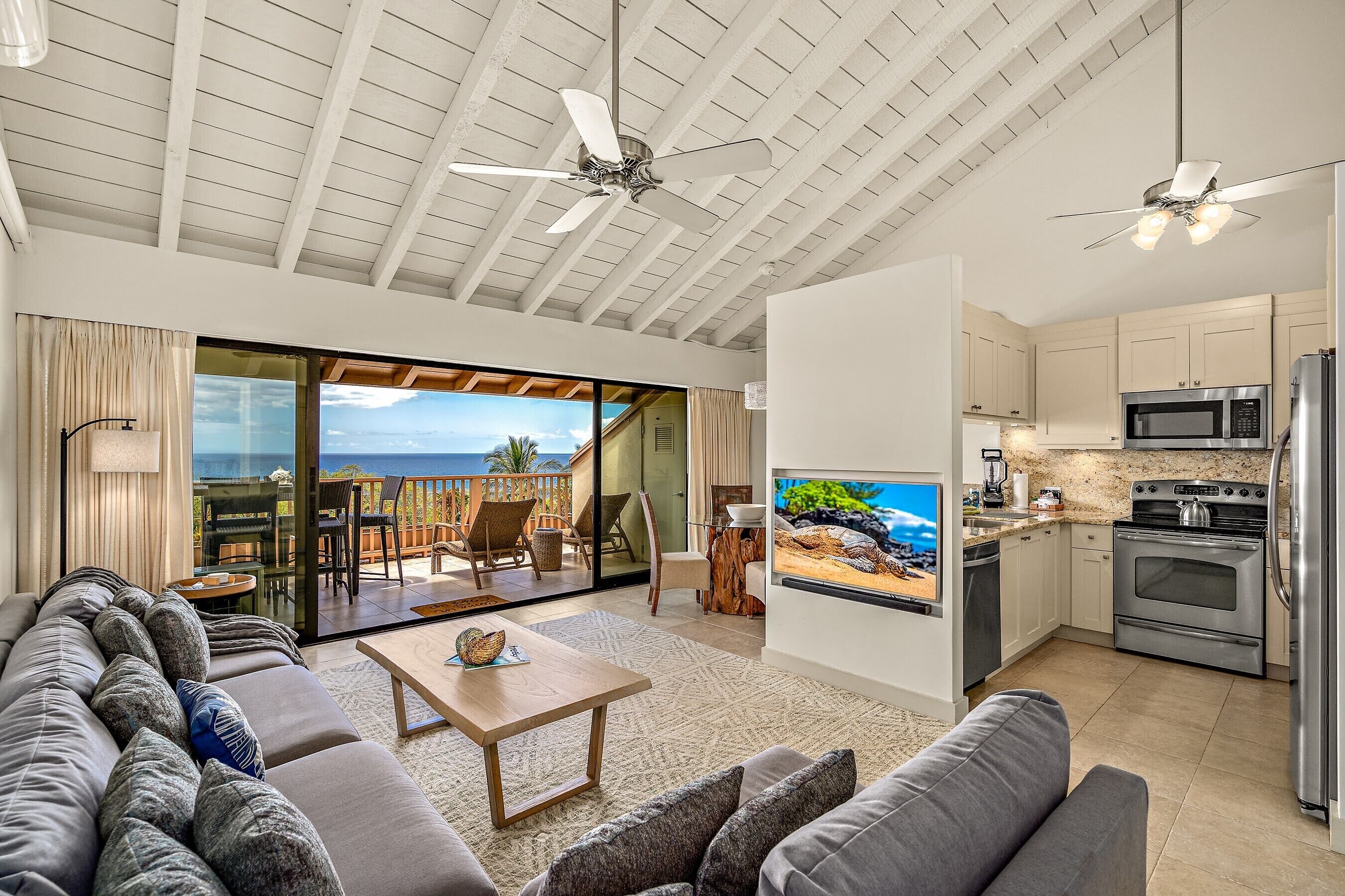 A spacious living area with a large sofa, a coffee table, and a kitchen with modern appliances.