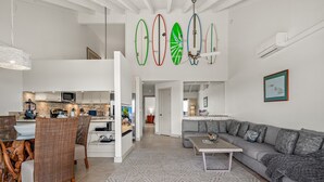 A spacious living area with a dining set, a sofa, and a ceiling fan.