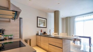 Una cocina moderna con una isla central, armarios de madera y un comedor con mesa y sillas.
