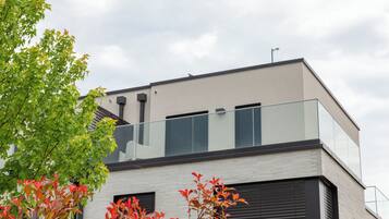 Een modern gebouw met een plat dak, grote ramen en een balkon.