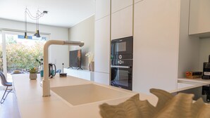 A modern kitchen with a white countertop, stainless steel appliances, and a view of the outdoors. - Reckenthal House (Strassen)