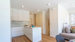 A compact kitchen with white cabinets, a small island, and a wooden floor.