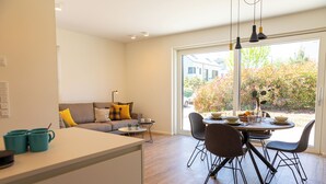 A modern kitchen with a dining area, a sofa with cushions, and a view of the outdoors. - Reckenthal House (Strassen)