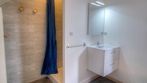 Ein Badezimmer mit Dusche, Waschbecken und Spiegel.