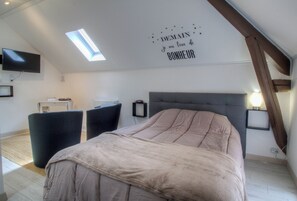 Relax in a serene bedroom with a large bed, flat-screen TV, and natural light pouring in from the skylight.