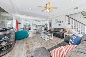 Ein geräumiges Wohnzimmer mit einem großen Sofa, einem Couchtisch und einem sesselartigen Möbelstück in Türkis.