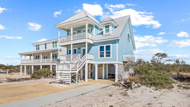 A two-story beachfront house with a balcony, a covered porch, and a sandy beach in the foreground. - Ocean+Lake Views~HEATED Pool~Pickleball~Golf Cart (Gulf Shores)