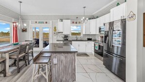 A modern kitchen with white cabinets, stainless steel appliances, and a large island. - Ocean+Lake Views~HEATED Pool~Pickleball~Golf Cart (Gulf Shores)